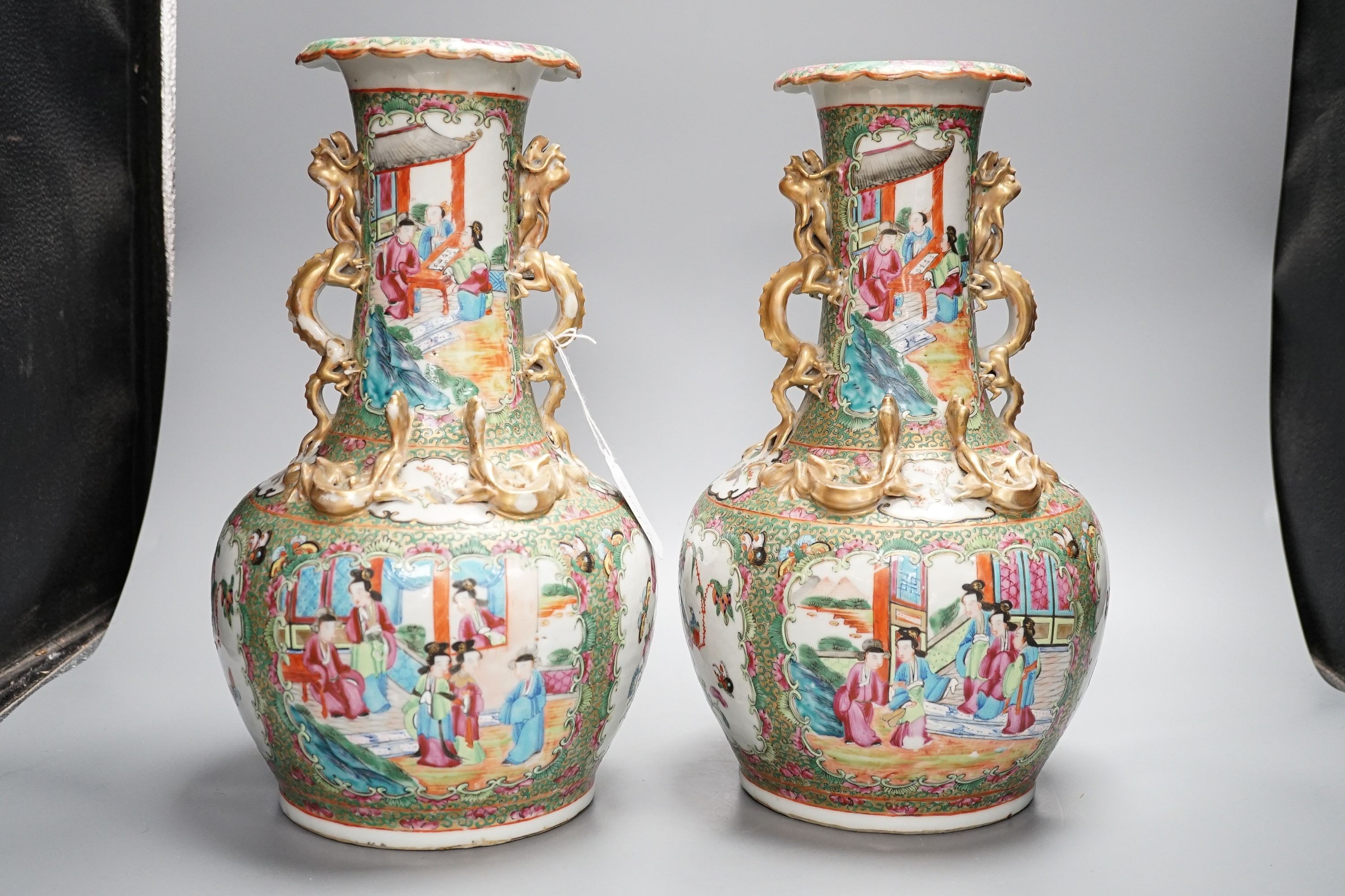 A pair of late 19th century Chinese famille rose vases, decorated with figures, birds and butterflies, twin lion dog handles, height 35cm